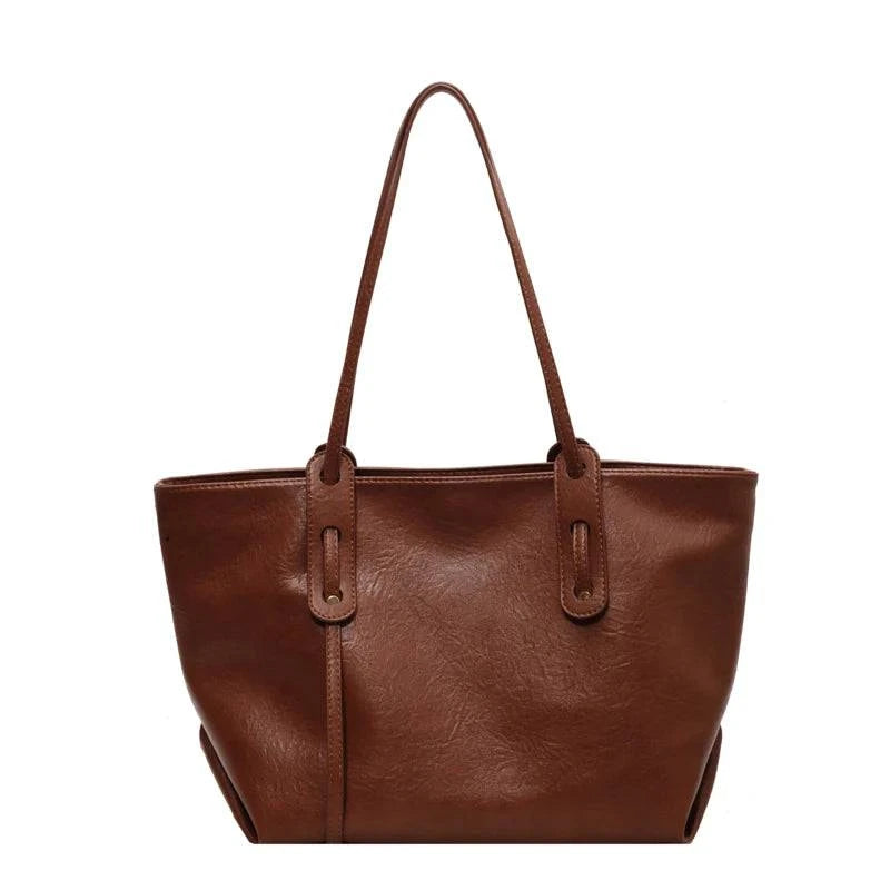 Bolsa tote feminina de couro marrom, design minimalista com alças longas e acabamento liso, vista de frente em fundo branco