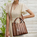 Bolsa tote de couro marrom com frisos verticais e pendente metálico, usada em look casual elegante.