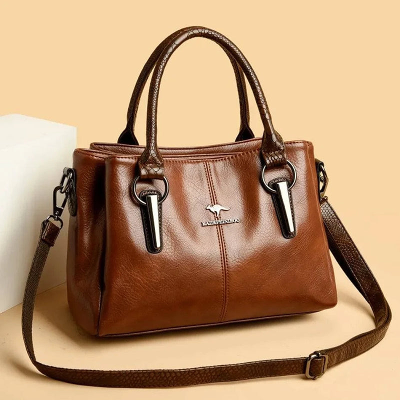 Bolsa Tote Feminina Couro Sublime marrom, acabamento brilhante, alças duplas. Logo metálico e ferragens prateadas. Elegante e versátil para o dia a dia.