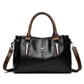 Bolsa Tote Feminina Couro Sublime preta. Alças duplas e transversal marrom com textura, ferragens metálicas e logo. Elegante e versátil.