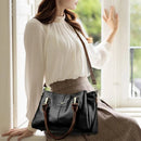 Bolsa tote de couro preta com alças marrom, modelo em blusa branca.
