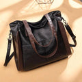 Bolsa tote feminina de couro sintético Sofia preta com detalhes marrons nas laterais e alças, design espaçoso e alça transversal removível para versatilidade.