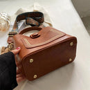 Bolsa tote de couro marrom com alça transversal e pés de metal dourado