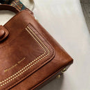 Bolsa tote marrom de couro com bolso frontal decorado com tachas douradas