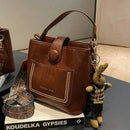 Bolsa tote de couro marrom com bolso frontal pesponto e alça transversal estampada