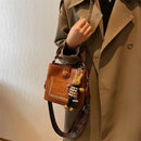 Bolsa tote de couro marrom com tachas, alça estampada e charm de coelho