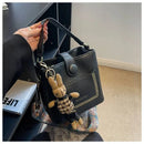 Bolsa tote preta de couro com bolso frontal com tachas, alça estampada e charm de coelho