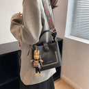 Bolsa tote preta com tachas douradas, alça estampada e charm de coelho em madeira
