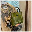 Bolsa tote verde com alça, detalhes em costura e charm de coelho