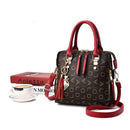 Bolsa tote estruturada marrom com alças borgonha, padrão geométrico dourado e charm decorativo