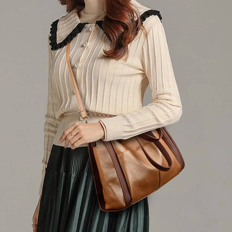 Mulher usando bolsa tote feminina de couro sintético Sofia em tom caramelo com alça transversal, combinando com blusa clara e saia escura, ideal para look de trabalho.