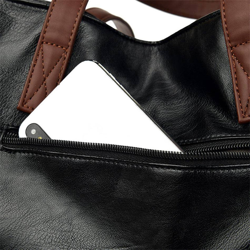 Detalhe do bolso traseiro com zíper na bolsa tote Sofia preta, mostrando um smartphone guardado e a textura do couro sintético, ideal para acesso rápido.