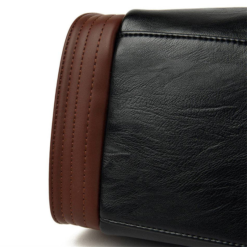 Detalhe lateral da bolsa tote Sofia preta, exibindo a faixa vertical marrom com costuras paralelas e a textura granulada do couro sintético preto.
