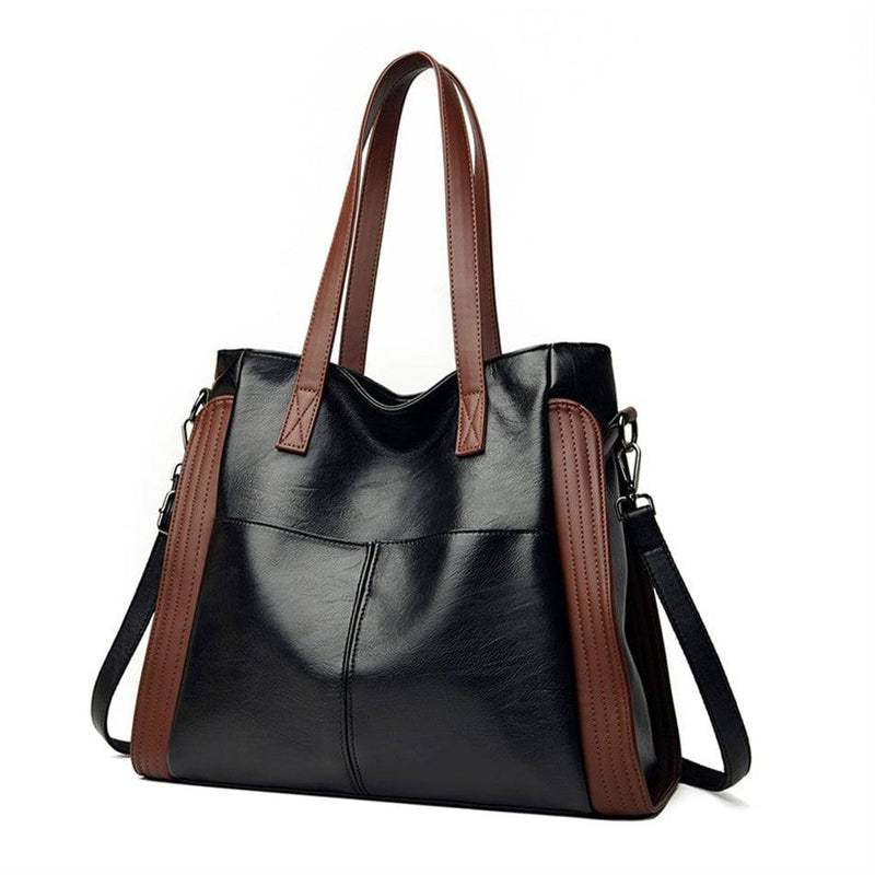 Bolsa tote feminina de couro sintético Sofia preta com laterais e alças marrons, design elegante e alça transversal caída, em vista frontal sobre fundo sutilmente cinza.