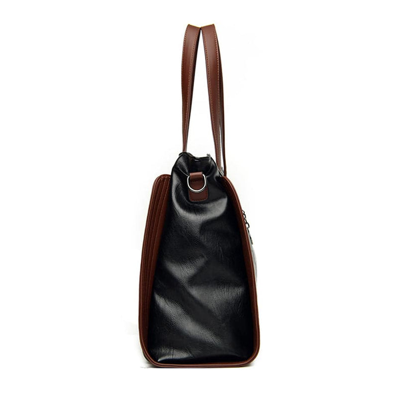 Perfil lateral da bolsa tote Sofia preta com detalhes marrons e alças de mão em destaque, evidenciando sua profundidade e o design estruturado, em fundo branco.