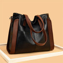 Bolsa tote preta de couro sintético com alças marrons e detalhes nas laterais