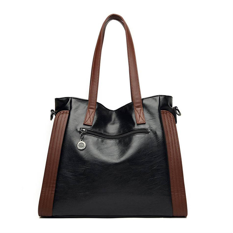 Parte traseira da bolsa tote Sofia preta com detalhes marrons, destacando o bolso com zíper e o puxador redondo, ideal para guardar itens pequenos com segurança.