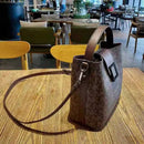 Bolsa transversal marrom com estampa monograma, fecho de aba com fivela e alça ajustável