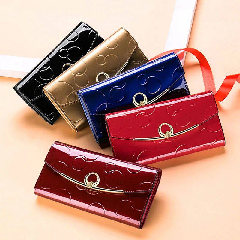 Coleção de carteiras femininas de couro genuíno de luxo em diversas cores (preta, dourada, azul, vermelha e vinho), todas com acabamento brilhante e design em relevo de círculos, dispostas em leque.