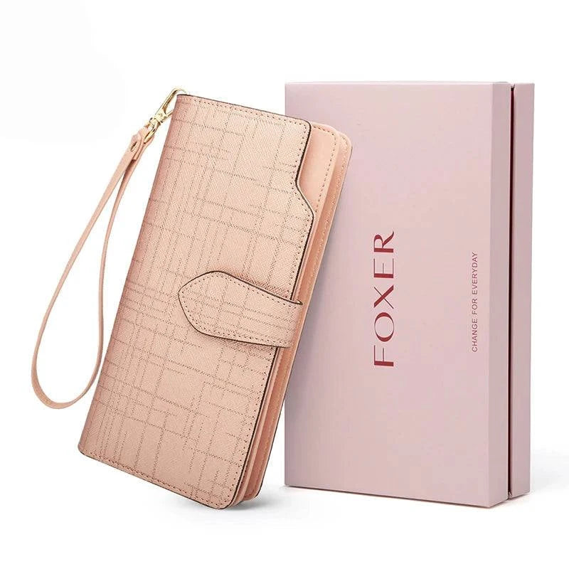 Carteira feminina de couro de luxo rosa claro com textura sutil quadriculada, alça de pulso removível e aba de fecho, exibida ao lado de sua caixa de presente rosa da marca "FOXER".