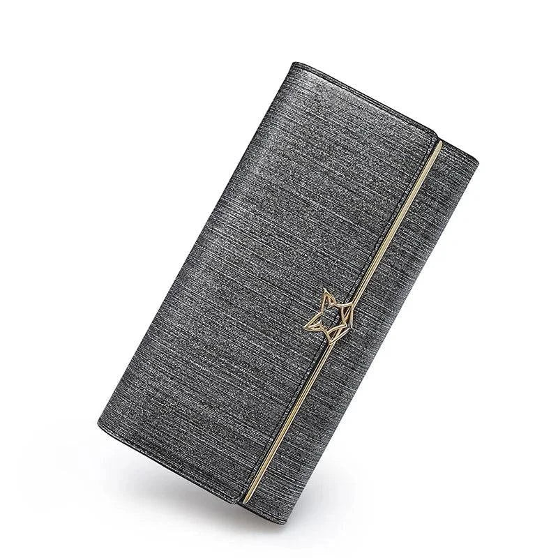 Carteira feminina de couro luxuosa cinza metálico com textura sutil e fecho de estrela dourado, exibida em ângulo dinâmico, design elegante e moderno