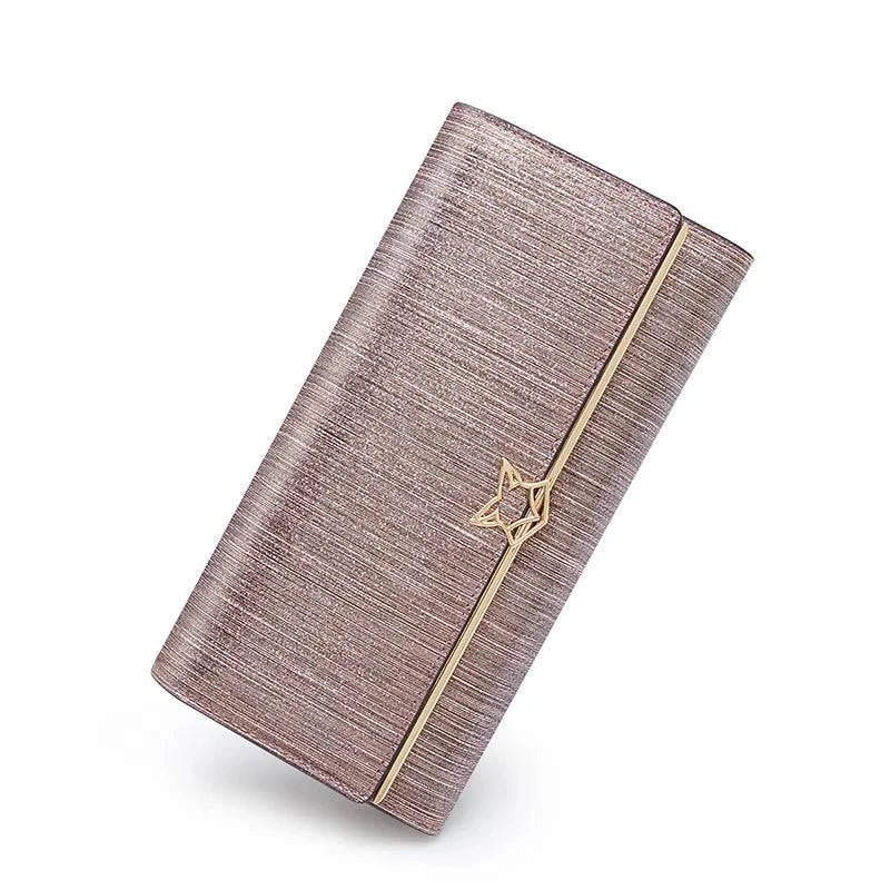 Carteira feminina de couro luxuosa rosa metálico com textura brilhante e fecho de estrela dourado, exibida em ângulo inclinado sobre fundo branco, sem caixa.