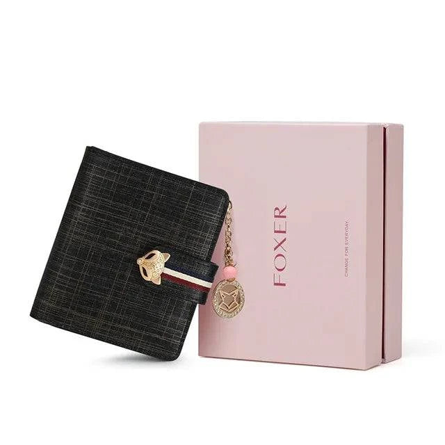 Carteira feminina pequena elegante preta com textura sutil e fecho de raposa dourado, acompanhada de sua caixa de presente rosa da marca "FOXER", ideal para presente.