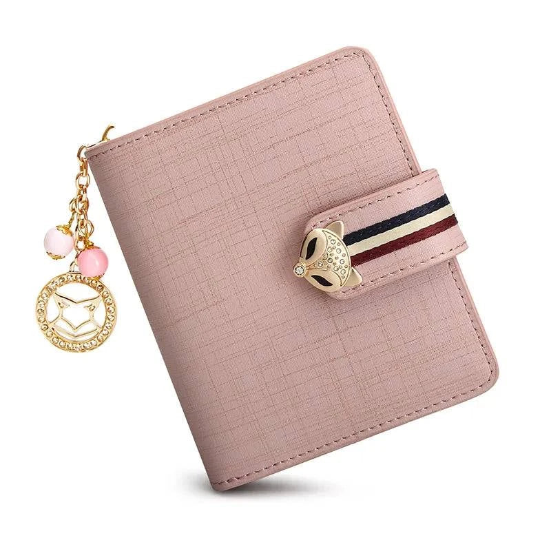 Carteira feminina pequena elegante rosa com textura suave, fecho de raposa metálico com strass e aba com tira listrada, exibida em vista frontal simples.