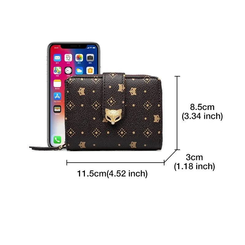 Carteira feminina pequena marrom com estampa e aba marrom com fecho de raposa, exibindo dimensões de 11.5cm de largura, 8.5cm de altura e 3cm de profundidade, com comparativo de tamanho com um smartphone.