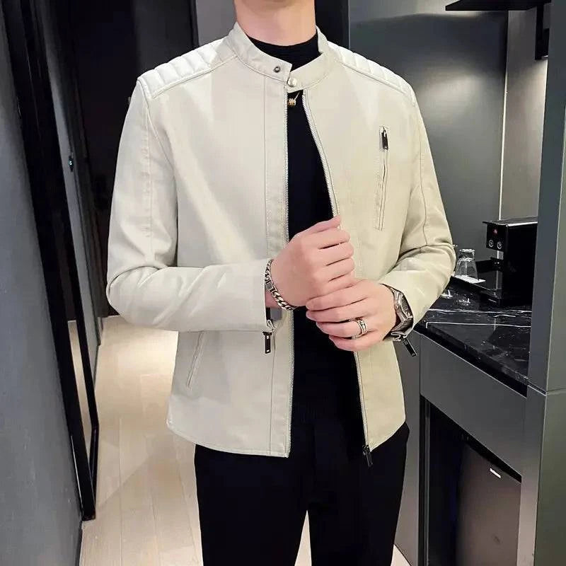 Homem usando jaqueta biker slim de couro sintético bege com gola mandarim e detalhes acolchoados nos ombros, exibindo anéis e pulseira. Estilo moderno e exclusivo, perfeito para o cenário cultural de Embu das Artes.