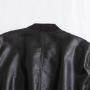 Detalhe da costura vertical traseira de jaqueta de couro preta feminina com gola canelada