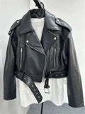 Jaqueta de couro feminina preta, estilo biker com cinto ajustável, lapelas largas, zíperes prateados e botões de pressão, transmitindo um visual de luxo e atitude.