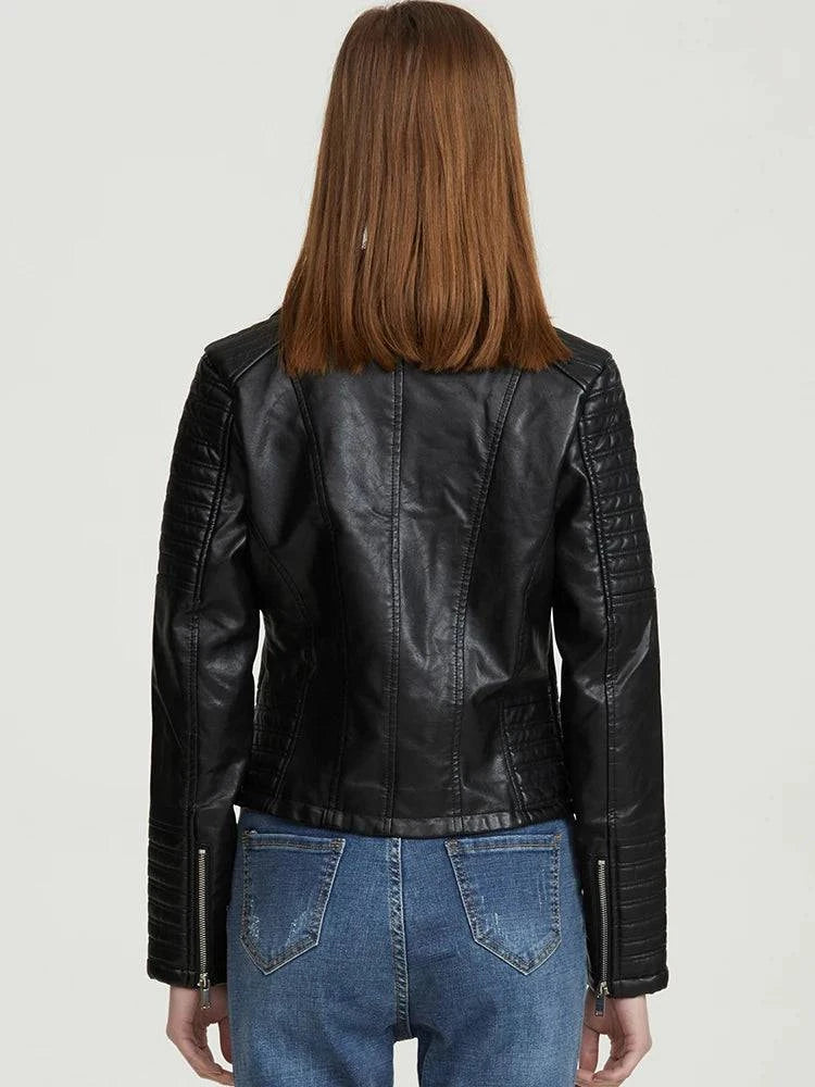Parte traseira da jaqueta de couro feminina Vogue Noir preta, com detalhes acolchoados nos braços e zíperes nos punhos, exibindo o caimento elegante e a qualidade premium da peça em uma modelo.