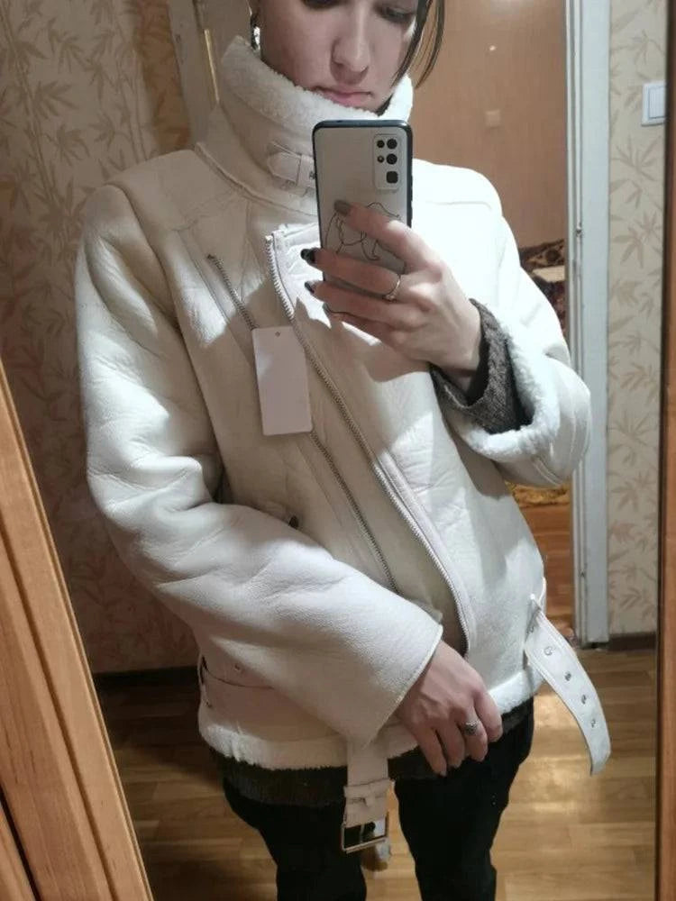 Mulher vestindo jaqueta de couro estilo aviador na cor branca ou off-white, com forro de pele sintética macia e gola alta, zíper assimétrico e cinto na barra, exalando um luxo aconchegante e exclusivo para o inverno.
