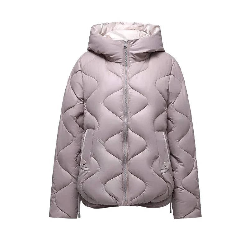 Jaqueta puffer feminina em tom cinza-claro sofisticado, com capuz e zíper, apresentando acolchoamento ondulado e acabamento elegante, ideal para o inverno com luxo discreto.