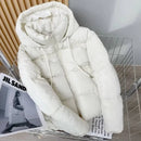 Jaqueta puffer branca acolchoada com capuz e zíper, exibida sobre revista de moda