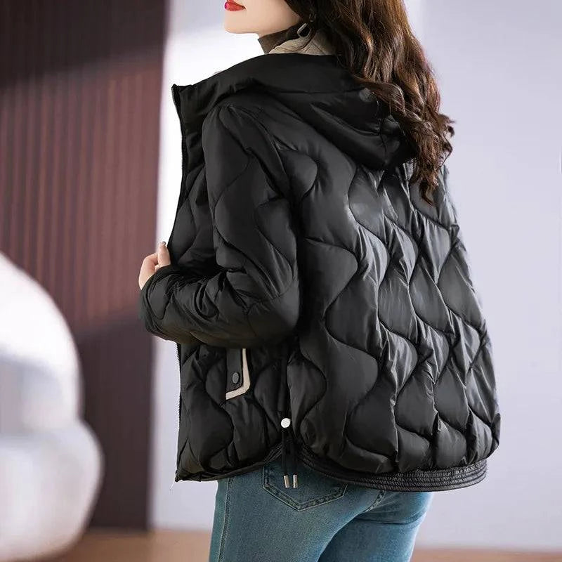 Parte traseira da jaqueta puffer feminina preta, destacando o acolchoamento exclusivo em padrão ondulado e o capuz, conferindo um visual sofisticado e aconchegante para o inverno.