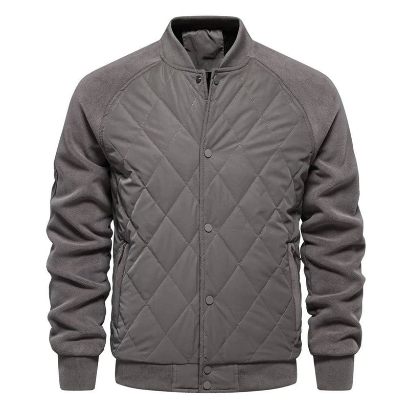 Jaqueta masculina bomber acolchoada com corpo em padrão de losangos cinza claro, mangas em tecido cinza escuro (fleece), gola, punhos e barra canelados cinza. Fechamento frontal com botões de pressão. Design moderno e versátil, combinando conforto e exclusividade.