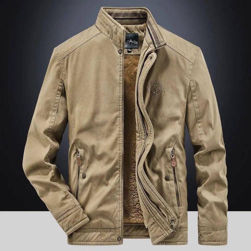 Jaqueta masculina bomber parka na cor cáqui, aberta para revelar o forro de pelúcia marrom escuro, com gola alta, zíperes e botões de pressão. O bordado "JP" no peito e os detalhes em couro nos puxadores conferem um estilo robusto e funcional, ideal para o clima de Embu das Artes.