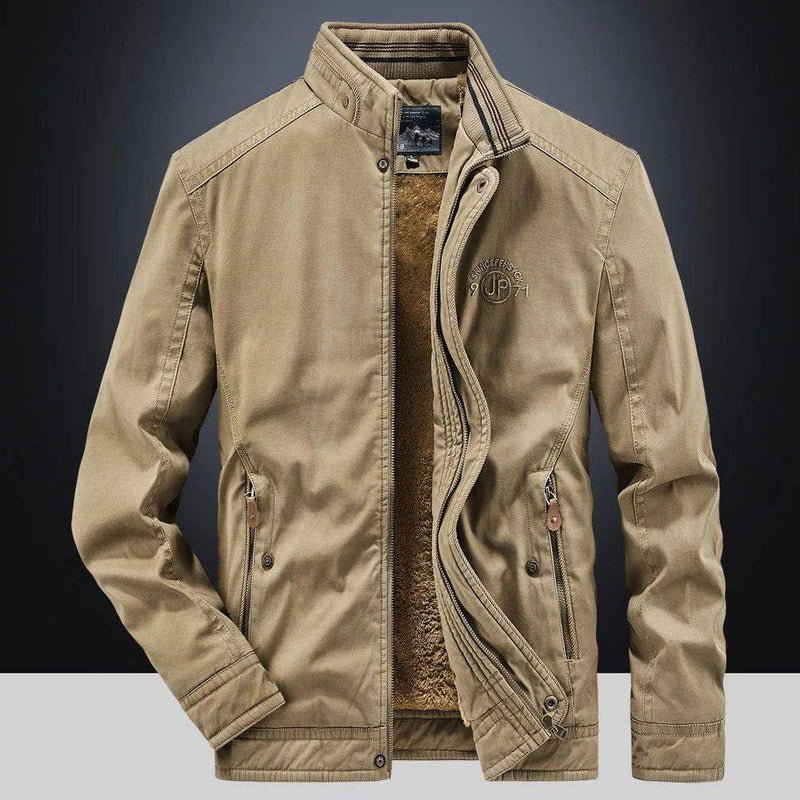 Jaqueta masculina bomber parka na cor cáqui, aberta revelando o forro de pelúcia marrom e a gola alta com detalhes canelados. Os zíperes e botões de pressão, juntamente com o bordado "JP" no peito, conferem um estilo robusto e funcional, ideal para o clima de Embu das Artes.