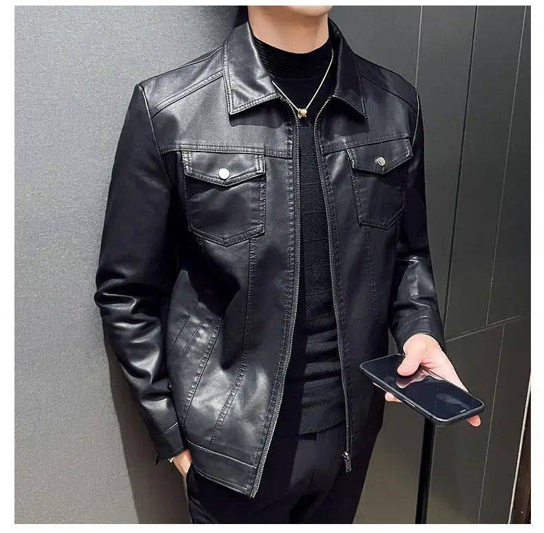 Homem vestindo jaqueta masculina de couro Heritage Rider preta com gola de camisa, bolsos frontais com lapelas e botões prateados, e fechamento em zíper, segurando um smartphone. A peça exala um estilo clássico e atemporal, sendo um item de herança que confere exclusividade e sofisticação ao visual em Embu das Artes.