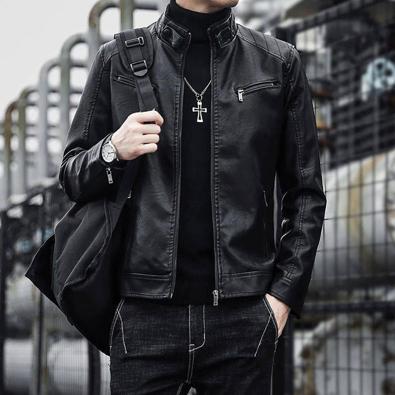 Homem usando jaqueta masculina de couro legítimo preta, estilo americano, com gola alta, zíperes prateados nos bolsos frontais e detalhes de costura nos ombros, sobre uma blusa de gola rolê preta e jeans escuros. Uma bolsa a tiracolo, relógio e colar de cruz complementam o visual robusto e autêntico, perfeito para um estilo exclusivo e duradouro.