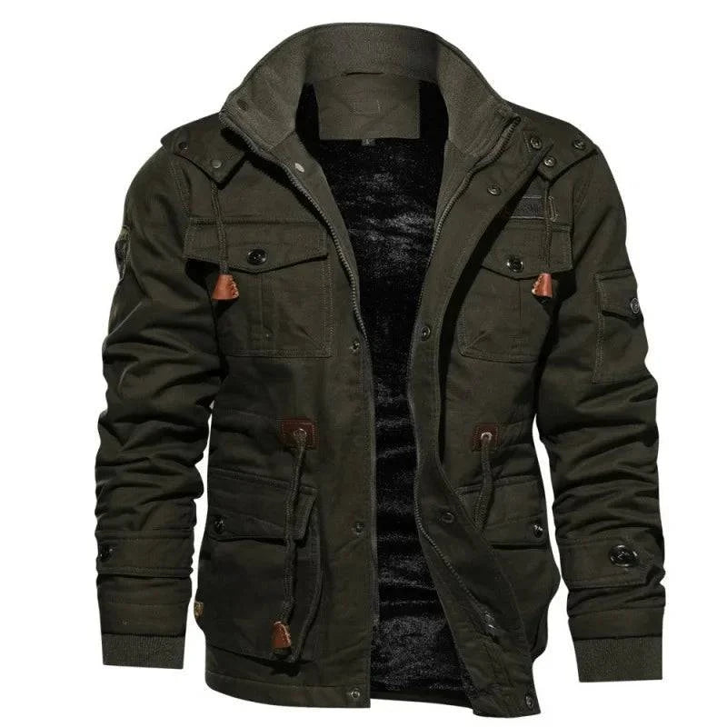 Jaqueta masculina militar forrada em verde musgo, aberta para revelar o forro de pelúcia preto e gola alta canelada. Possui múltiplos bolsos utilitários com botões e detalhes em couro marrom, oferecendo um estilo robusto e funcional para o inverno.