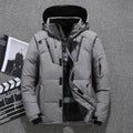 Homem vestindo jaqueta masculina parka acolchoada cinza com capuz preto, múltiplos bolsos com zíperes vermelhos e pretos, e fechamento frontal com zíper e botões de pressão, em um ambiente interno com elementos de produção cinematográfica ao fundo. Uma peça moderna e funcional, ideal para quem busca um estilo exclusivo e prático para o clima de Embu das Artes.
