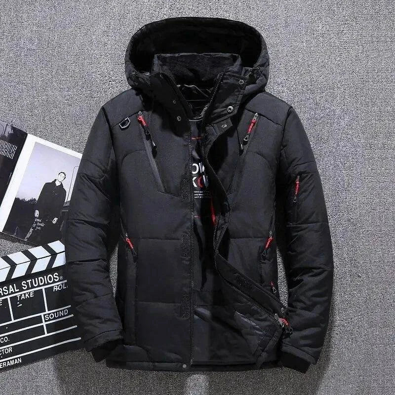 Jaqueta masculina parka acolchoada preta com capuz, múltiplos bolsos frontais com zíperes vermelhos e pretos, e fechamento com botões de pressão e zíper, em um fundo que remete a um estúdio de cinema. Design robusto e funcional, ideal para um visual de alta performance no clima de Embu das Artes.
