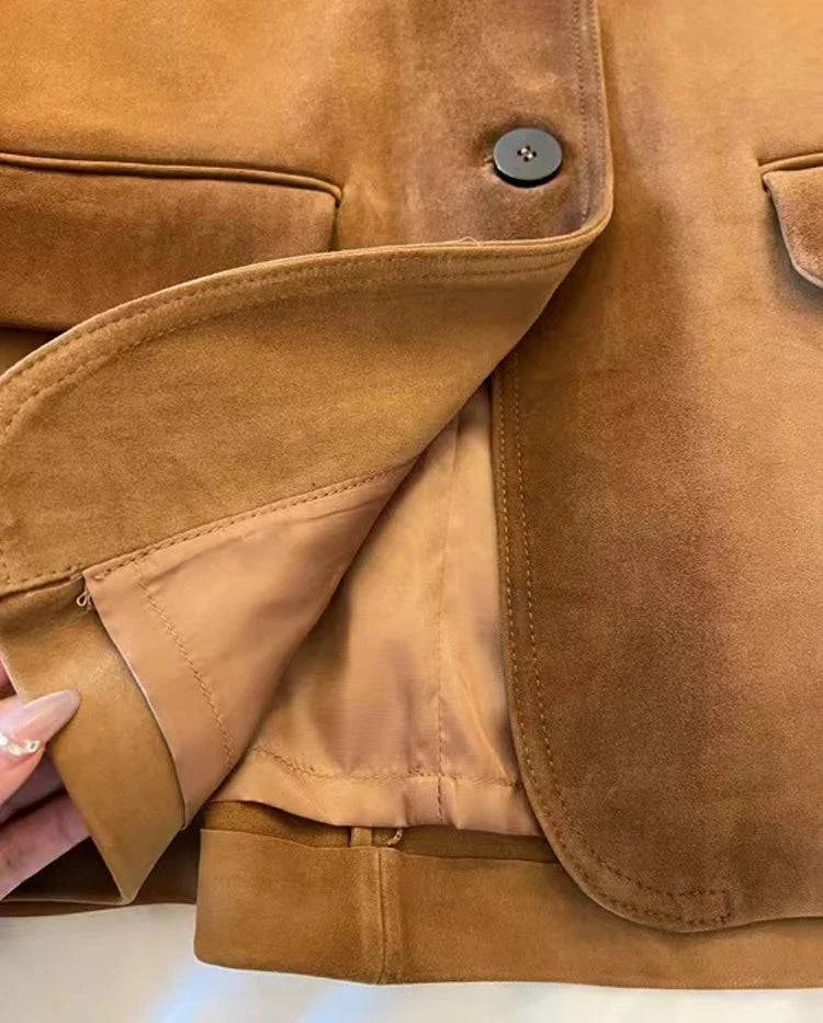 Detalhe de perto da jaqueta de pele de carneiro vintage caramelo, mostrando a textura aveludada, um botão e o forro interno, evidenciando o acabamento impecável e a qualidade superior dos materiais de luxo.