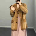 Mulher vestindo jaqueta de pele de carneiro vintage feminina caramelo, estilo blazer com botões escuros e bolsos grandes, combinada com vestido rosa e clutch, exalando um luxo raro e sofisticado.