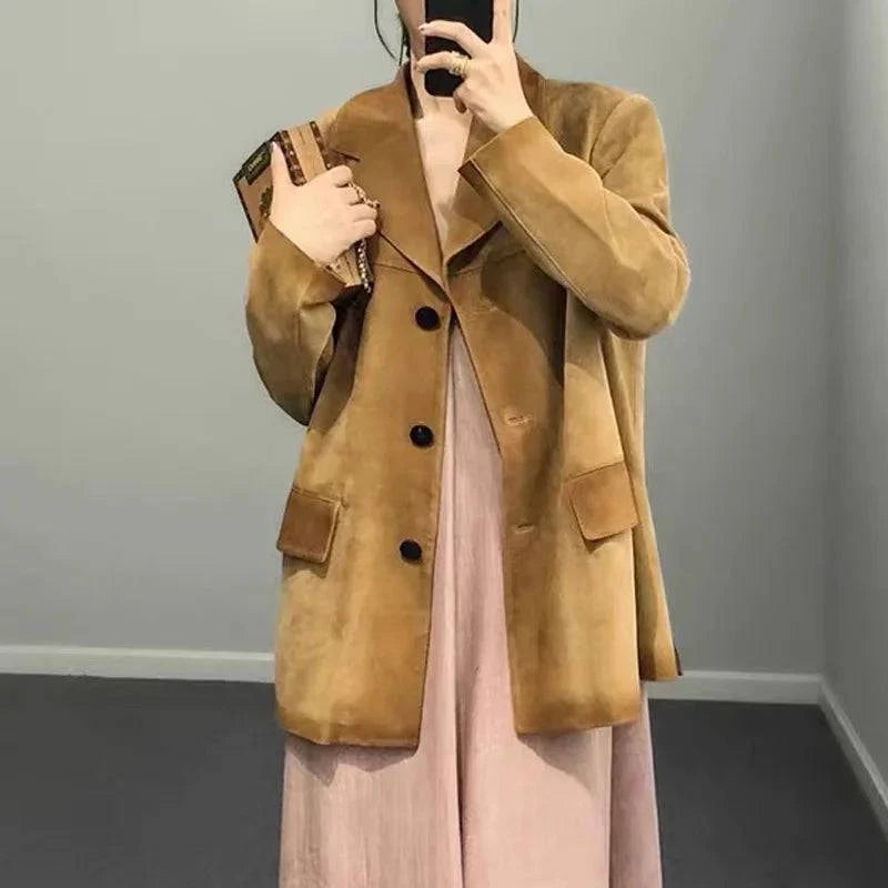 Mulher vestindo jaqueta de pele de carneiro vintage feminina caramelo, estilo blazer com botões escuros e bolsos grandes, combinada com vestido rosa e clutch, exalando um luxo raro e sofisticado.