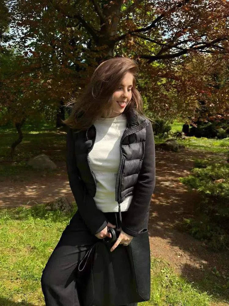 Mulher sorrindo em parque, usando jaqueta puffer feminina preta com detalhes em moletom nas mangas, destacando o estilo casual sofisticado e a versatilidade.