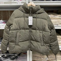 Jaqueta puffer feminina verde militar, com capuz e cordões, acolchoamento térmico e zíper frontal, exibindo um estilo utilitário de luxo e aquecimento essencial para o inverno.